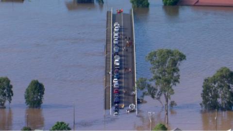 Cars trapped on bridge surrounded by floodwaters