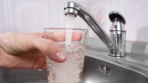 A man filling a glass with tap water