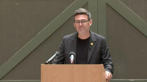 Burnham smiling in front of a lectern during his speech