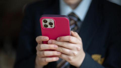 A 12-year-old school boy looks at a iPhone screen.
