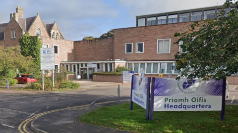 Highland Council headquarters building in Inverness, with a purple sign outside and trees on a sunny day