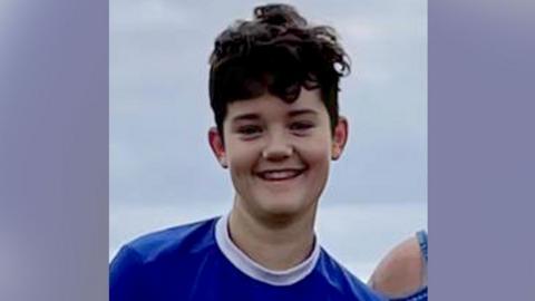 Kai Lloyd smiling at the camera in a blue football top