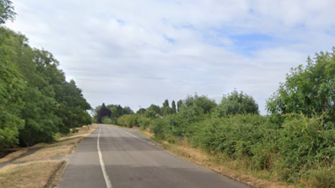 A rural country road with fields on either side 