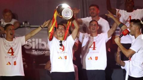 Match winner Mikel Oyarzabal holds the Henri Delaunay Trophy aloft as he celebrates with his team-mates on stage