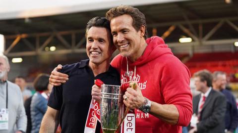Rob McElhenney and Ryan Reynolds holding trophy
