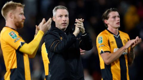 Cambridge boss Neil Harris and his players applaud their travelling supporters following the game at Craven Cottage