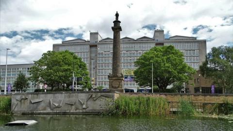 Hull College main building with the pond of Queens Gardens in the foreground and the column of the Wilberforce Monument in the middle 