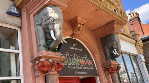 Two elephant head busts on either side of the door to Victoria Snooker Club in Tunbridge Wells