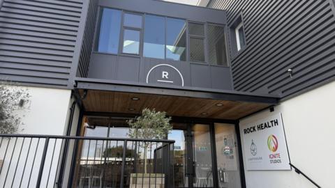 A picture of the entrance of Ignite Studios. There are several steps leading up to glass doors.  