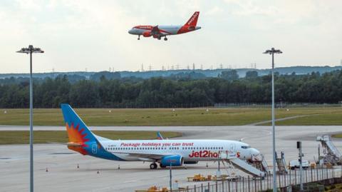 Planes at Heathrow, with one in air and one on tarmac