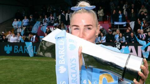 Alex Greenwood lifting and kissing the WSL trophy last season