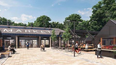 An artist impression of how the market will look, showing s single storey building with the word 'market' on the roof behind a wide flagged square with a bicycle rack to the right of it, seating to the left, and right next to more buildings in brown with pointed roofs. People are milling about