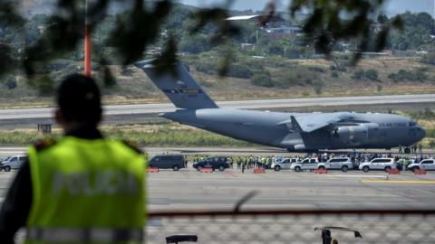 A Colombian police officer stands guard as a US Air Force C-17 aircraft carrying food and medicine for Venezuela arrives at the Camilo Daza International Airport in Cucuta, Colombia, 16 February 2019