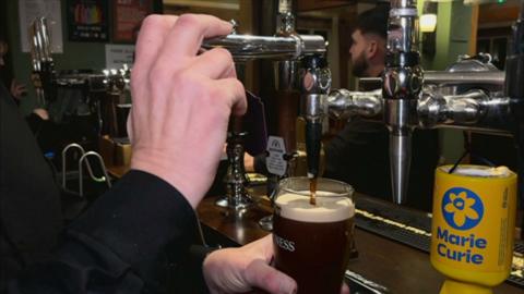 A glass of Guinness is poured in a pub bar