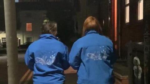 Two women walking away down a street