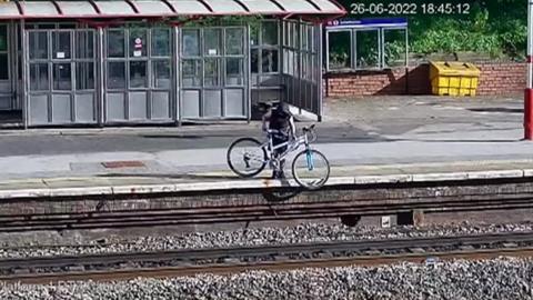 Teenager throwing bike onto railway line