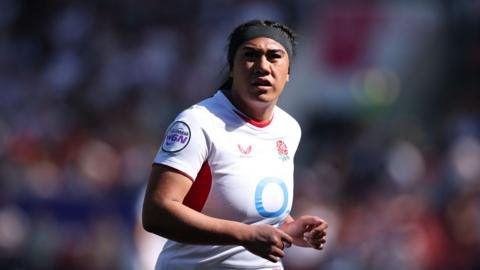 Haineala Lutui running and wearing a white England shirt, She has dark hair and a black headband.