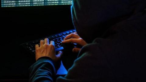 A man sat at a computer typing on a keyboard. 