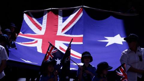 School children march with an Australian flag in the Australia Day Parde on January 26, 2014