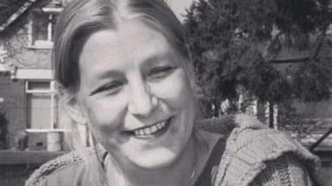 A black and white picture of Dawn Sturgess, smiling at the camera, wearing a knitted cardigan
