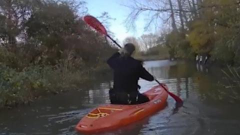 A Sussex police officer rowing through flood water in a kayak