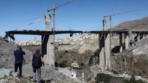 People stand near the B1 bridge damaged by a strike, as the U.S.-Israeli conflict with Iran continues, in Karaj, Iran, April 3, 2026
