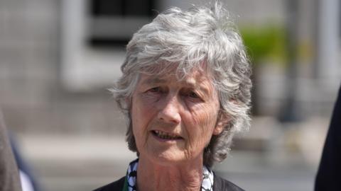 Catherine Connolly has short grey hair and is speaking as the picture is taken. The background behind her is blurred.