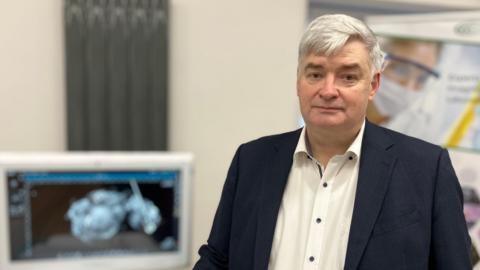 Hugh Cormican has short grey hair and is wearing a navy suit and white shirt.