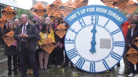 Lid Dem leader Ed Davey in front of a giant clock in Windsor