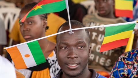 A man displays the flags of Mali, Niger and Burkina Faso during a rally in Bamako, Mali - 1 February 2024