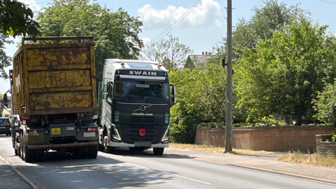 Two lorries drive past each other on either side of Burton Road