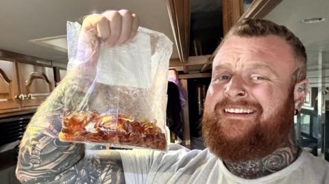 Nathan Rimmington holds up a bag of cola bottle sweets.