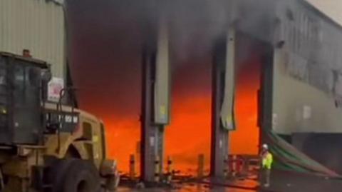 The orange glow of a fire inside a large industrial building