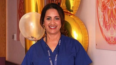 A midwife standing front of balloons in a hospital corridor