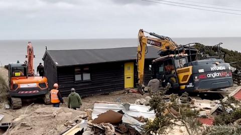 A clifftop homeowner facing a demolition order hires heavy lifting equipment to move his bungalow.