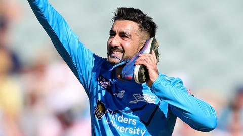 Tabraiz Shamsi celebrates by holding his shoe to his ear
