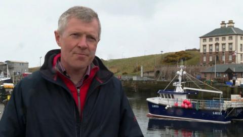 Scottish Liberal Democrat leader Willie Rennie stands in front of a boat in Eyemouth