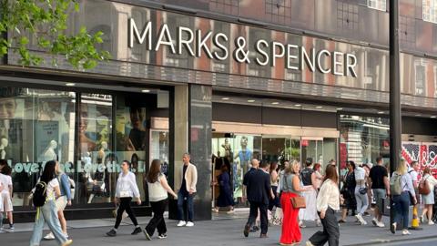 People walk in front of M&S store on Oxford Street, central London