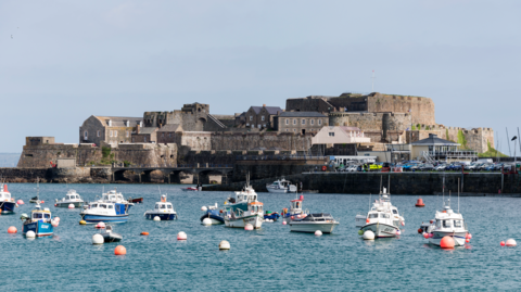 Castle Cornet is a large island castle in Guernsey, with boats in front in the sea