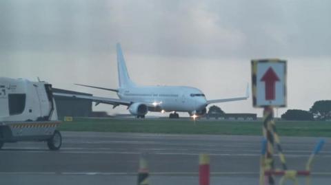 A white jet plane makes its way along the tarmac at Newquay Airport in Cornwall as it prepares to take off.