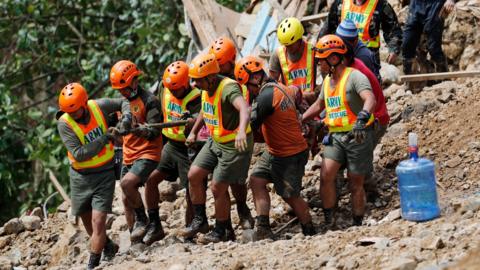 Rescue volunteers carry the body of a landslide victim caused by Typhoon Mangkhut during rescue efforts in Ucab village, Itogon town, Benguet Province, Philippines, 17 September 2018