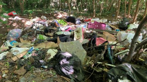 Piles of rubbish are scattered across woodlands including toys, bin bags and broken plastic chairs