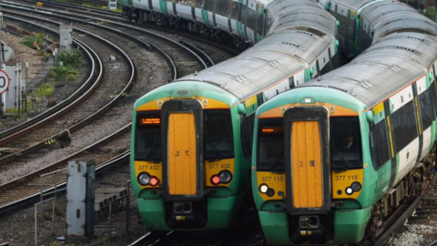 Two Southern Railway trains, in their green, white and yellow livery, sit side by side on a stretch of track.