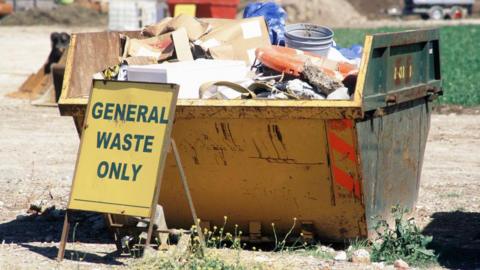 A skip is seen filled with rubbish