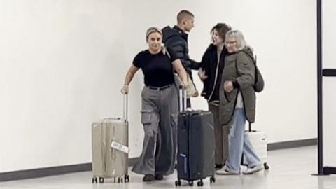 Bella Culley arrives at Luton Airport as her mum pushes two suitcases