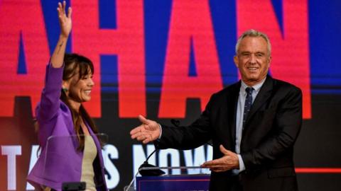 Independent presidential candidate Robert F. Kennedy, Jr. gestures next to Nicole Shanahan as she becomes the vice presidential candidate of Kennedy, in Oakland, California