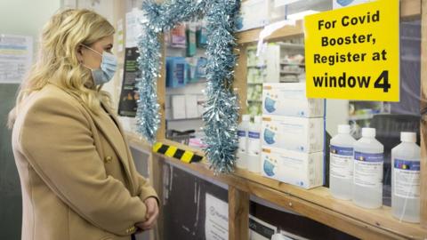 A woman waits in line at the Aneurin Evans community pharmacy on December 8, 2021 in Barry