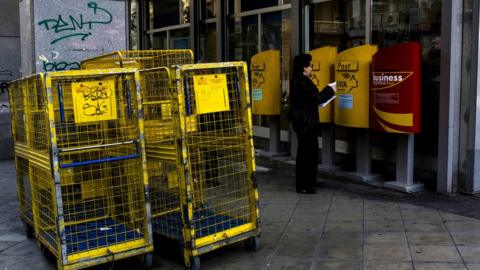 A woman posts a letter in the Greek capital at a post office on March 17