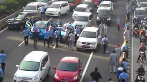 Protestors in Jakarta attacking a cab for not also protesting