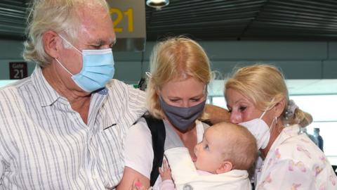 Grandparents greet a mother and her baby at a Queensland airport on Monday
